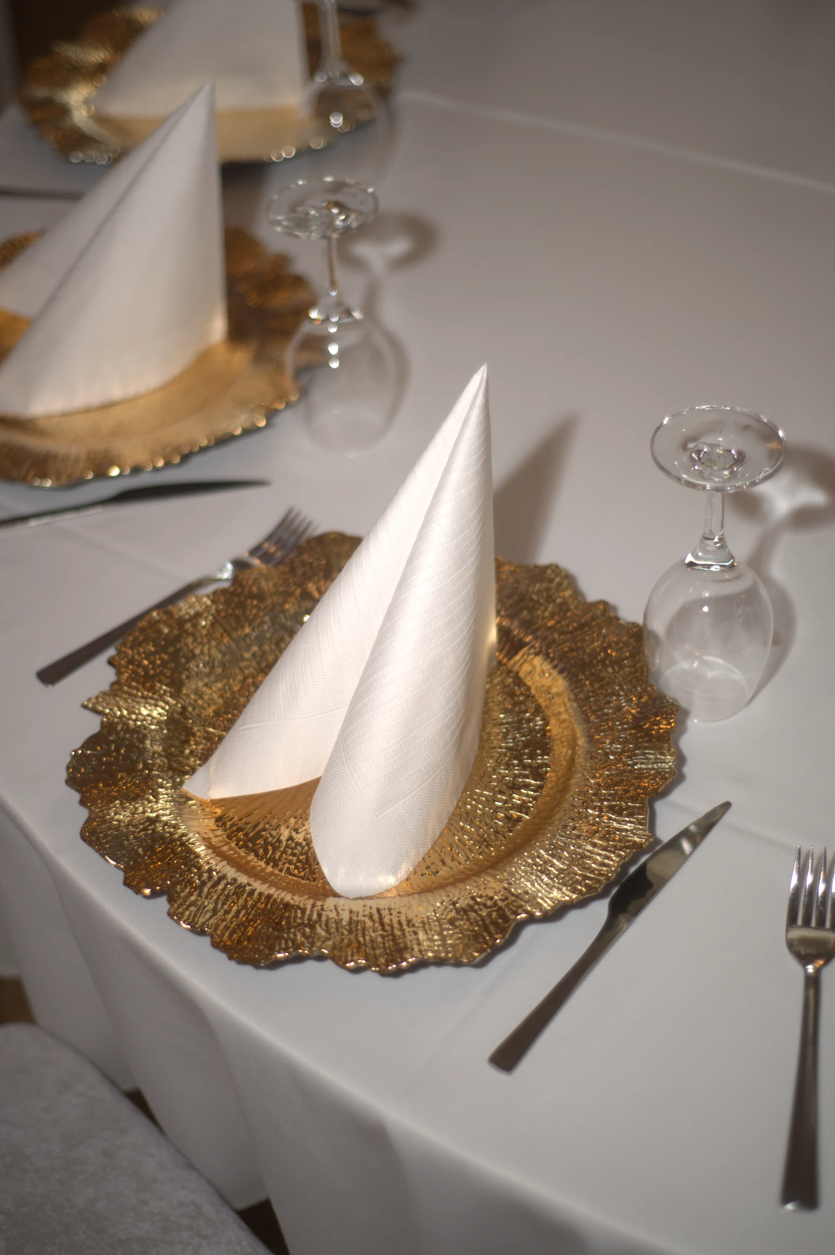 Feine Tischgestaltung mit goldenen Platztellern und Kerzen